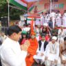 मुख्यमंत्री डॉ. मोहन यादव ग्वालियर में हर घर तिरंगा अभियान के तहत आयोजित कार्यक्रम में महापुरुषों की वेशभूषा में सजे बच्चों का अभिवादन करते हुए, पृष्ठभूमि में बैंड दल और मंच पर तिरंगा अभियान का पोस्टर।