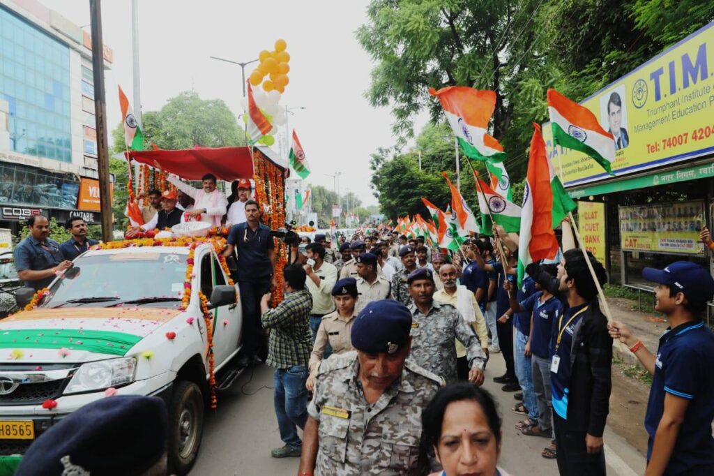 ग्वालियर में तिरंगा यात्रा के दौरान सड़क किनारे खड़े लोग और पुलिस बल तिरंगे लहराते हुए, आगे सजाए गए वाहन पर मुख्यमंत्री डॉ. मोहन यादव और अन्य नेता।